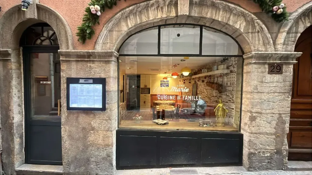 Façade du Bistrot Marie au 29 rue du Bœuf, dans le Vieux-Lyon (69005). Restaurant de cuisine de famille lyonnaise, installé dans une belle bâtisse en pierre du quartier Saint-Jean, à deux pas du métro Saint-Jean. Enseigne "Cuisine de Famille" visible en vitrine