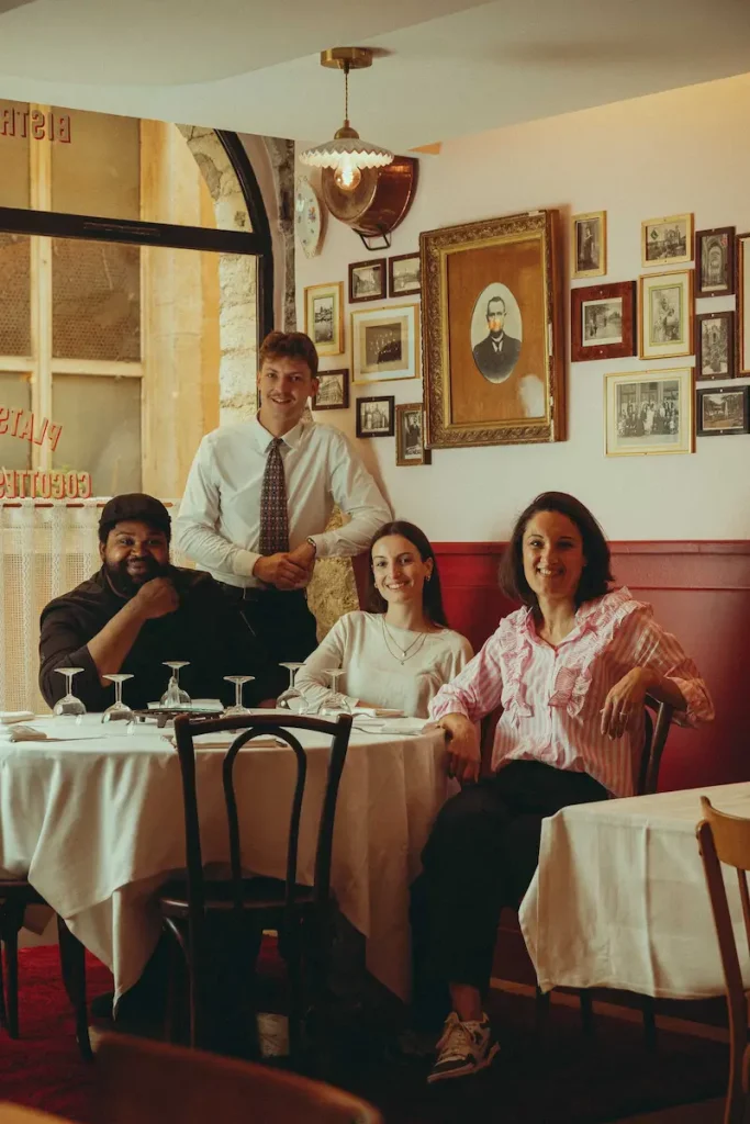 A PROPOS 2 Équipe du Bistrot Marie réunie en salle devant le mur de cadres anciens avec banquette rouge Lyon 5 - Photo © Mathilda Perrot