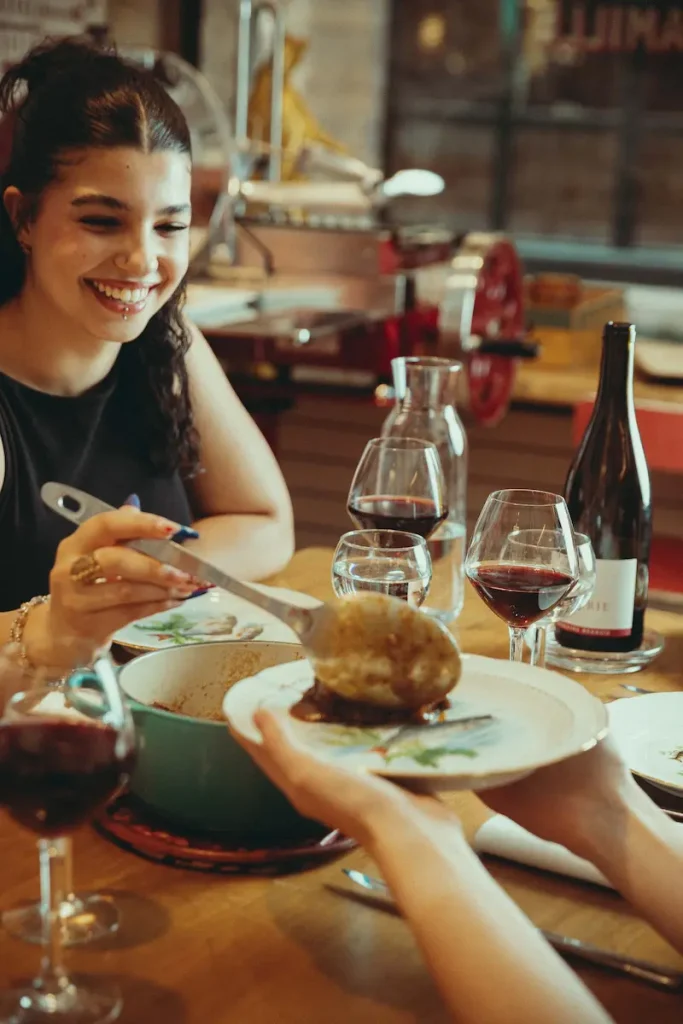 Convive souriante servant un plat mijoté depuis une cocotte en fonte verte à table au Bistrot Marie, Vieux-Lyon