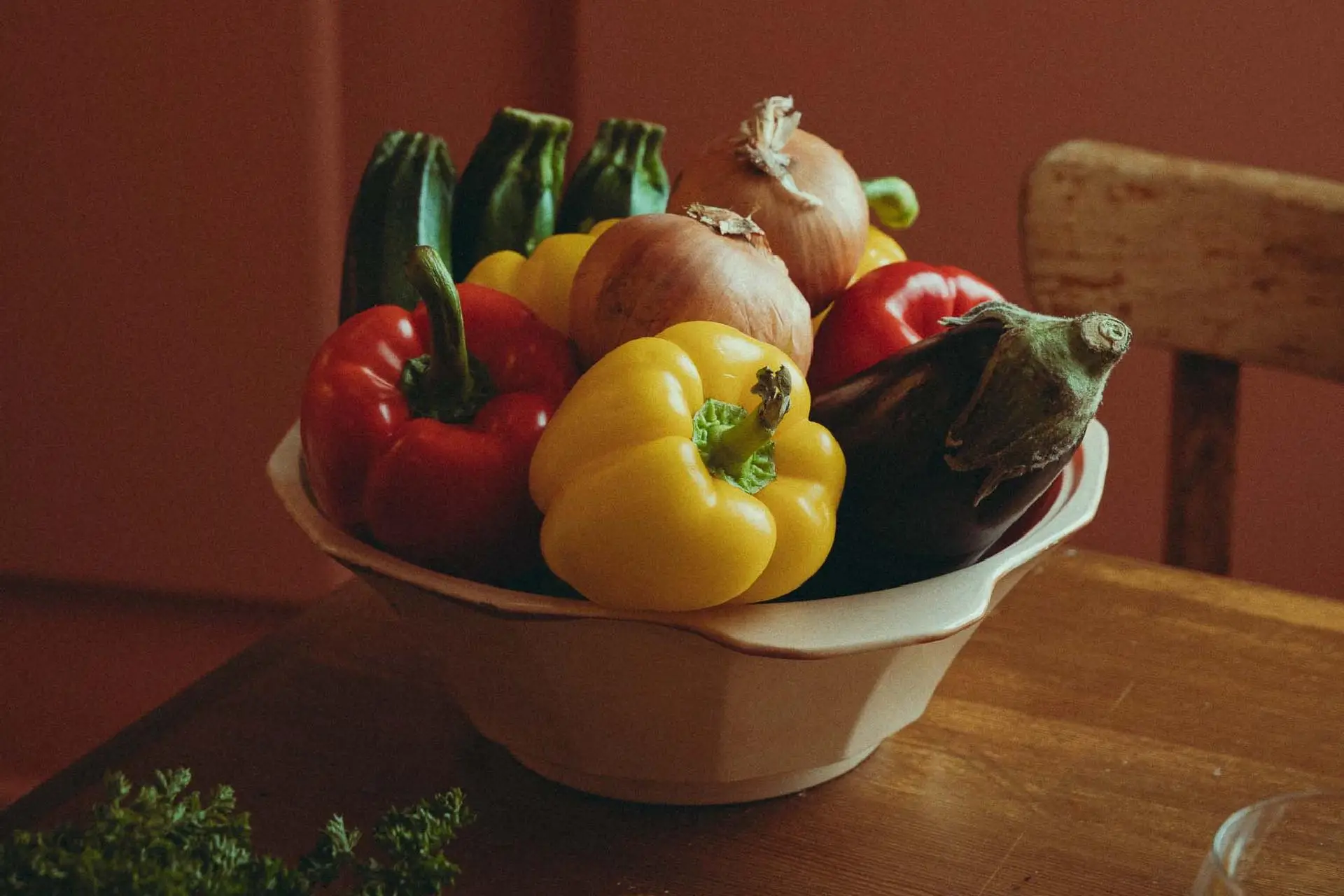 Saladier de légumes frais — poivrons, courgettes, aubergine, oignons — sur une table en bois au Bistrot Marie