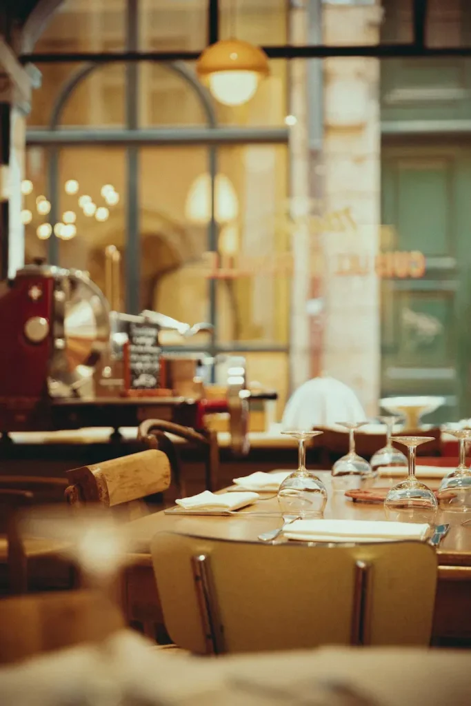 A PROPOS 3 Table de bistrot dressée avec verres en cristal et serviettes blanches dans la salle chaleureuse du Bistrot Marie Vieux-Lyon - Photo © Mathilda Perrot