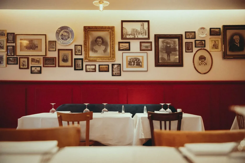 CONTACT 1 Tables nappées de blanc et chaises de bistrot sous les affiches anciennes et cuivres du Bistrot Marie, Vieux-Lyon